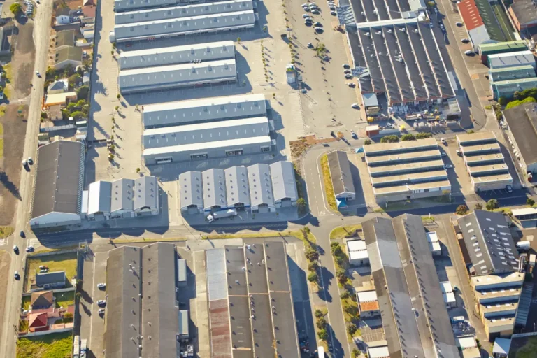Aerial view of an industrial estate with factory buildings, warehouses and access roads, illustrating factory development in Thailand.